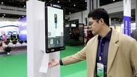 Seorang peserta pameran menunjukkan distributor kertas tisu otomatis dengan deteksi wajah. Istimewa/Xinhuanet.