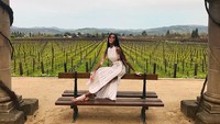 Wanita 24 tahun ini nampak eksotis saat mengenakan gaun putih. Makin seru karena pemotretan berlangsung di kebun anggur. Foto: Instagram winnieharlow