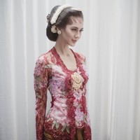 Ketika melakukan ritual adat siraman, pilihan kebaya tampak lebih berani dengan nuansa merah rancangan Poppy Karim. Kebaya model kutubaru tersebut tampil mencuri atensi dengan motif bunga bernuansa pink sebagai padanannya. Foto: Dok. David Salim Photography