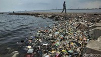 Warga melintas di tumpukan sampah plastik di Pantai Cilincing, Jakarta Utara, Senin (26/11).