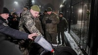 Warga tampak menyiramkan bensin ke tumpukan ban yang disusun di depan Kedubes Rusia. REUTERS/Gleb Garanich.