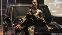 Seorang model dengan busana militer duduk di kap mobil Mercedes-AMG G 63 Edition 1.