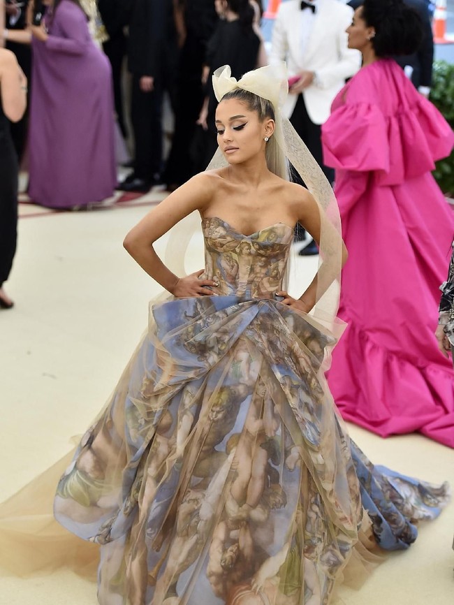 Ariana Grande menghadiri Met Gala di 2018. Ia tampil heboh dengan ballgown bermotif lukisan dan hair piece pita raksasa. (Foto: Getty Images)