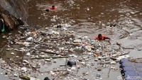 Petugas kebersihan sedang mengumpulkan sampah yang hanyut di Pintu Air Manggarai, Jakarta, Selasa (27/11/2018).