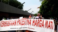 Spanduk bertulisan dukungan untuk Palestina nampak dalam unjuk rasa tersebut.