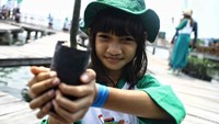 Seorang anak terlihat memamerkan mangrove di depan kamera.