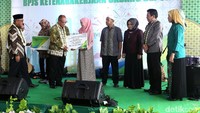 Agus Susanto menyerahkan santunan jaminan kematian dan jaminan hari tua kepada salah satu warga.