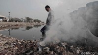 Warga sedang membakar sampah plastik yang telah dikumpulkan dari area di sekitar tanggul laut Pelabuhan Muara Baru.