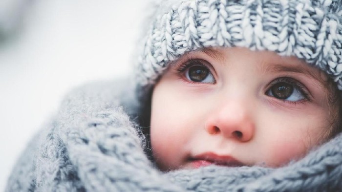 dreamy cozy outdoor portrait of toddler child girl in winter, wearing grey knitted hat and scarf