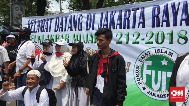 Massa Reuni Aksi 212 Antre Foto di Balik Spanduk Bela Tauhid