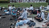 Anak-anak yang kelelahan beristihat dengan tidur beralaskan tikar di kawasan Monas.