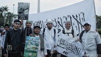 Beberapa peserta reuni foto bersama dengan latar belakang bendera tauhid.