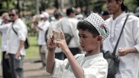 Seorang anak mengabadikan suasana Reuni 212.