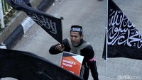 Massa yang hadir dan memenuhi kawasan Monas sejak pagi hari itu sebagian besar menggunakan pakaian serba putih dan membawa beberapa atribut. Tapi ada juga kok yang berpakaian serba hitam lengkap dengan atribut bendera hitam bertuliskan kalimat tauhid seperti ini.