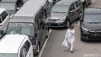 Seorang peserta Reuni 212 berjalan di antara kendaraan yang terjebak macet.