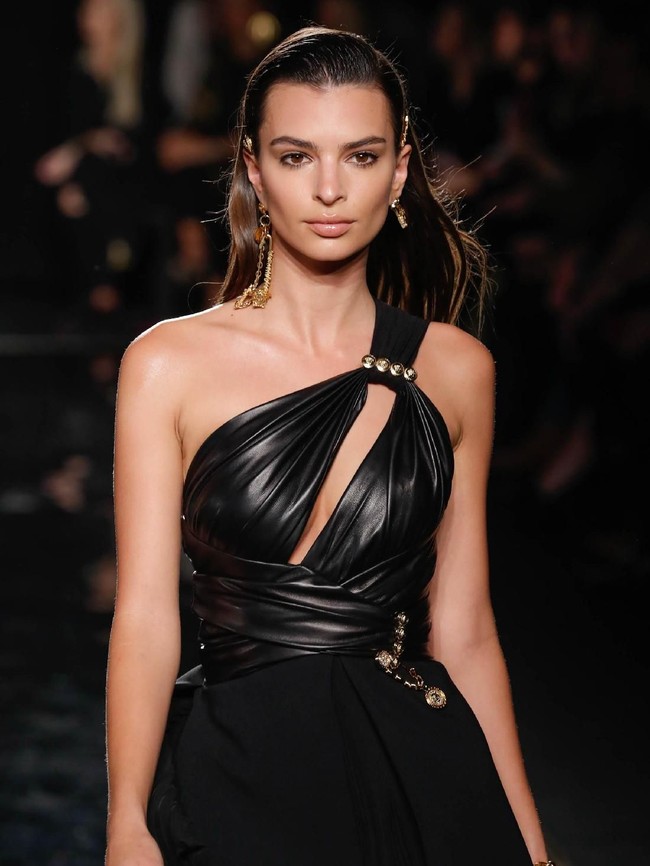 Si seksi Emily Ratajkowski diberi mandat untuk memeragakan sebuah dress hitam berbahan kulit. Detail cut-out gaun sekses mengakomodasi karakter Emily yang seduktif. (Foto: Getty Images)