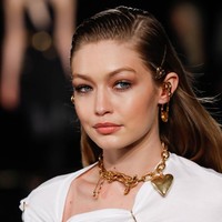 Di jajaran aksesori, Gigi menyempurnakan gayanya dengan kalung rantai keemasan dan anting unik berbentuk peniti yang menancap di telinga. (Foto: Getty Images)