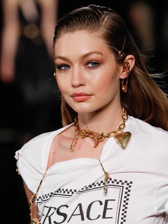 Di jajaran aksesori, Gigi menyempurnakan gayanya dengan kalung rantai keemasan dan anting unik berbentuk peniti yang menancap di telinga. (Foto: Getty Images)