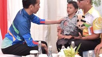 Jokowi terlihat menyerahkan kaki palsu kepada Adul yang berada di pangkuan Menteri Sosial Agus Gumiwang. (Foto: Foto: Biro Pers Setpres)