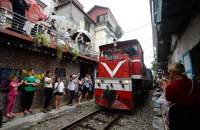 Kereta pun cukup sering lewat. Bukannya menghindari, banyak orang justru menunggu di samping rel untuk kereta itu lewat dan mengabadikan momennya. Foto: AFP
