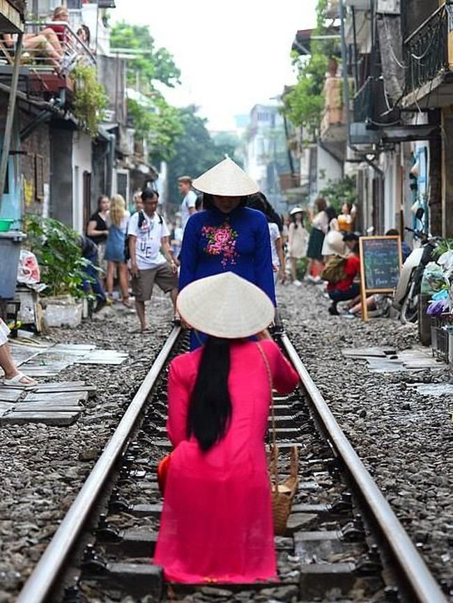 Turis lokal maupun mancanegara antre untuk mengambil gambar di tengah rel kereta api. Selayaknya pemotretan, beberapa di antara mereka bahkan mempersiapkan busana spesial seperti para wanita yang mengenakan pakaian tradisional ini. Foto: AFP