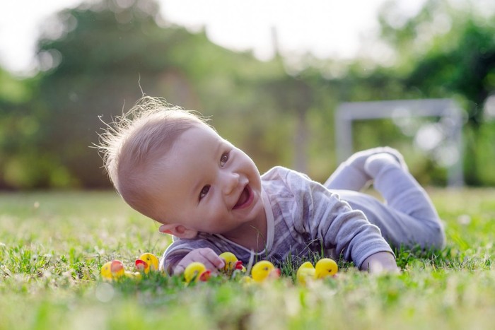 ilustrasi bayi Happy baby girl sitting in a meadow, holding a buttercup flower.