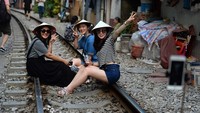 Bermodalkan tongsis, mereka pun eksis. Dengan topi capil khas Vietnam, mereka sudah sah liburan ke negeri eksotis ini. (AFP/Getty Images)