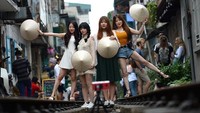 Inilah tren yang tengah digandrungi para turis yang liburan ke Hanoi, Vietnam. Mereka rela berburu foto anti mainstream di atas rel kereta yang Instagramable ini. (AFP/Getty Images)