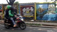 Pemotor melintas di depan mural Joko Widodo dan Prabowo Subianto di Jalan Juanda.