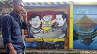 Pejalan kaki melintas di depan mural Joko Widodo dan Prabowo Subianto di Jalan Juanda, Depok, Jawa Barat, Rabu (5/12/2018).