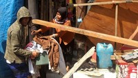 Warga mengeluarkan barang-barangnya dari rumah yang tertimpa crane.