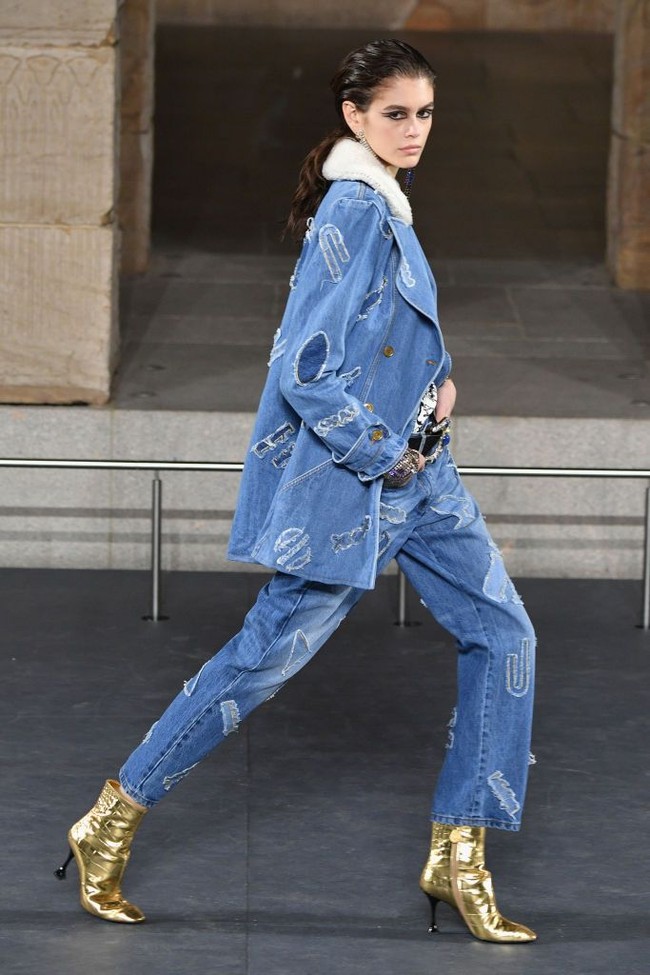 Selain Pharrell,  tampil pula model Kaia Gerber. Ia diberi mandat untuk memeragakan setenal denim yang menginjeksikan sentuhan urban di tengah dominasi busana bernuansa emas dan penuh detail beading ini. Foto: Dok. Getty Images