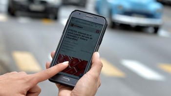 Seorang wanita menggunakan ponselnya untuk terhubung ke internet melalui WiFi di Havana, pada 5 Desember 2018. YAMIL LAGE /AFP.