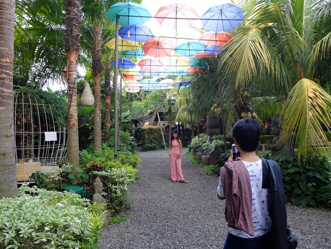 Pengunjung berfoto di bawah instalasi payung warna-warni. Untuk memasuki area Big Garden Corner, pengunjung dikenakan biaya tertentu. Tiket masuk wisatawan domestik dibanderol Rp 30 ribu dan sudah termasuk minuman kemasan. Foto: Daniel Ngantung/Wolipop