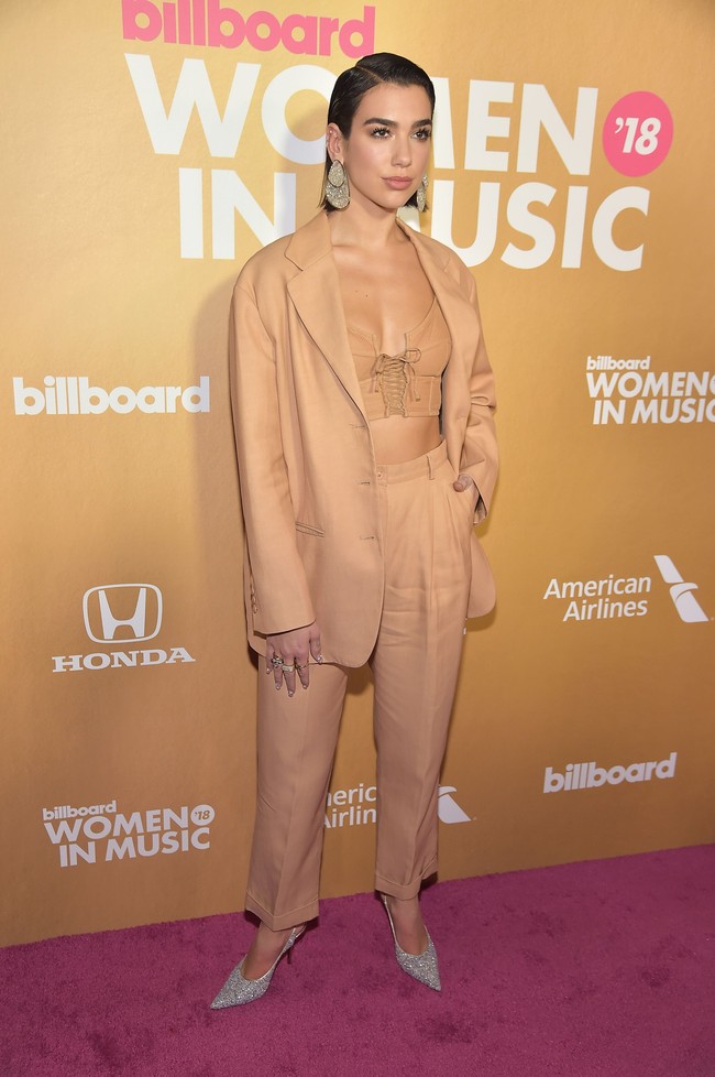 Dua Lipa tampil maskulin dengan setelan warna coklat, dari atas sampai bawah yang kini tengah menjadi tren fashion dunia. Pelantun One Kiss ini memberikan sentuhan yang seksi dengan bustier sebagai padanannya, dan membuat look itu tampil mewah berkat anting dan sepatu perak. Foto: Dok. Getty Images