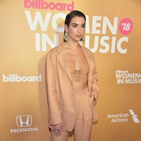 Dua Lipa tampil maskulin dengan setelan warna coklat, dari atas sampai bawah yang kini tengah menjadi tren fashion dunia. Pelantun One Kiss ini memberikan sentuhan yang seksi dengan bustier sebagai padanannya, dan membuat look itu tampil mewah berkat anting dan sepatu perak. Foto: Dok. Getty Images