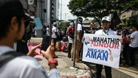 Massa membawa beraneka spanduk dan tulisan. Salah satunya adalah yang mendesak PM Malaysia Mahathir Mohamad untuk mundur (Foto: AFP)