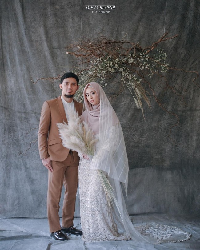 Atlet wushu Lindswell Kwok baru saja menggelar pernikahannya bersama Achmad Hulaefi beberapa waktu lalu. Merayakan pernikahannya, Lindswell dan Hulaefi melakukan foto pasca menikah dengan konsep sederhana, namun manis dibalut gaun pengantin putih yang syari. Hiasan hanging garden dari bunga kering sebagai latar pun membuat foto ini terasa modern namun romantis. Foto: Dok. Diera Bachir