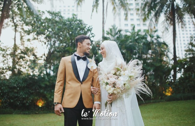 Sementara sang mempelai pria, Achmad Hulaefi, terlihat mengenakan setelan jas berwarna cokelat dan celana hitam serta dasi kupu-kupuh hitam. Hulaefi melengkapi penampilannya dengan korsase yang serasi dengan buket bunga mempelai wanitanya, Lindswell Kwok. Foto: lemotionphoto for detikSport