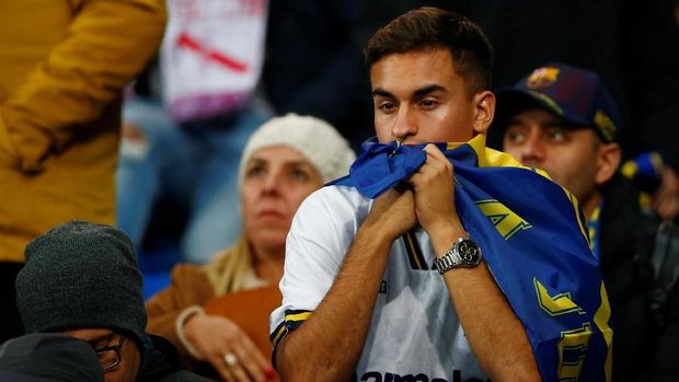 Fan Boca Juniors tertunduk lesu usai tim kesayangannya kalah 1-3 dari River Plate.