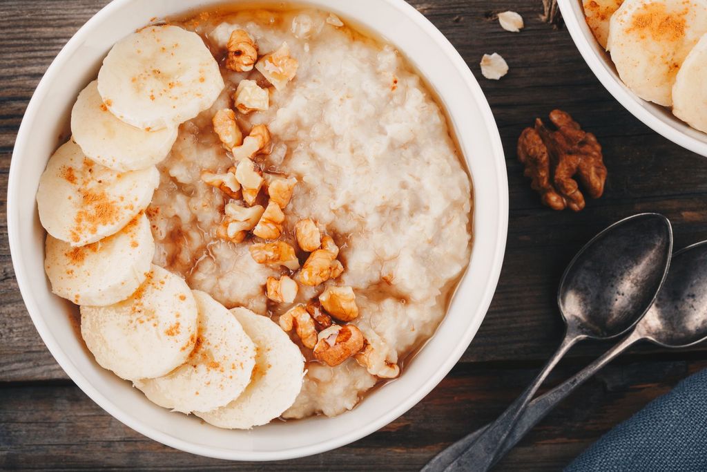 healthy breakfast bowl. oatmeal with banana, walnuts, chia seeds and honey on wooden background