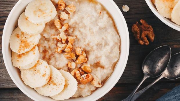 healthy breakfast bowl. oatmeal with banana, walnuts, chia seeds and honey on wooden background