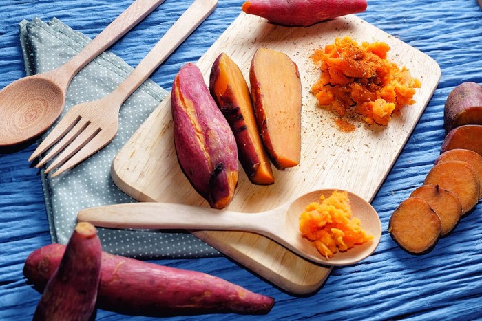 makanan pengganti nasi Sweet Potato on wooden cutting board with blue wood background
