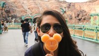 Pilot cantik ini sedang berada di Disney Sea Tokyo dan terlihat sedang menikmati es krim Mickey Mouse berwarna oranye yang menggemaskan. oto: Instagram @athirafarina