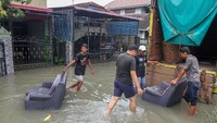 Warga mengeluarkan perabotan rumah tangga dari dalam rumah yang terendam banjir di Perumahan Sidomulyo, Kota Pekanbaru, Riau. ANTARA FOTO/Rony Muharrman.