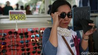 Seorang pembeli menjajal barang dagangan kacamata saat melintasi Skybridge atau Jembatan Penyeberangan Multiguna (JPM) Tanah Abang itu. 