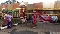 Anak-anak berjalan di depan Mapolsek Ciracas yang tertutup tripleks.