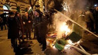 Para demonstran membakar tong sampah di sela aksi unjuk rasa di depan gedung Parlemen Hungaria. Massa pun meneriakkan Perdana Menteri Hungaria, Viktor Orban sebagai penghianat karena mendorong undang-undang tenaga kerja itu untuk disahkan.
