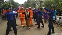 Satu tim pemadam yang menggunakan seragam dan peralatan menyambut sang pengantin untuk menuju pelaminan. 