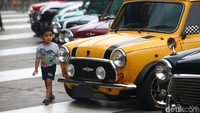 Seorang anak melintas di depan deretan mobil Mini Cooper.